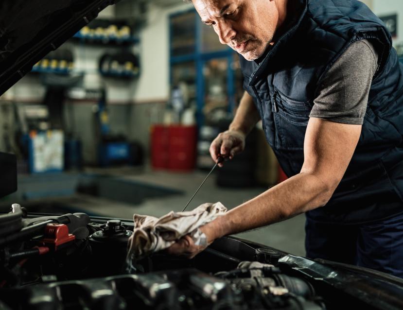 mecanicien-automobile-verifiant-l-huile-dans-le-moteur-de-la-voiture-tout-en-travaillant-dans-un-atelier-de-reparation-automobile