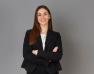 Femme souriante habillé en blazer noir sur un fond gris