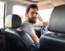 un homme barbu au volant d'une voiture se retournant vers l'arrière