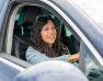 femme souriante au volant d'une voiture avec des lunettes de soleil sur la tete