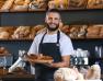 Boulanger qui tient une tarte devant son étale de pains 